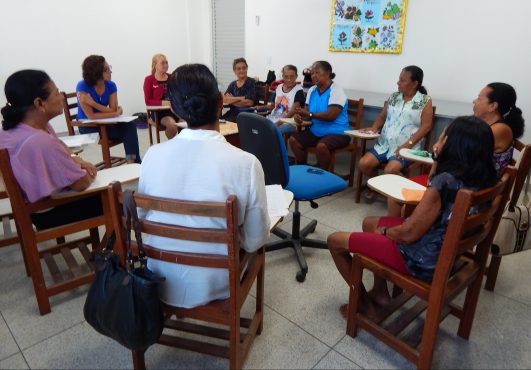 Grupo de moradores rurais sentados em cadeiras de madeira em um círculo de conversa (Foto: Nucom)