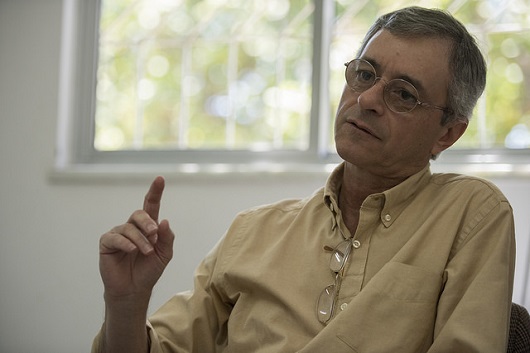 Professor Renato Sílvio sentado e levantando o braço em tom de explicação (Foto: Jr. Panela/UFC)