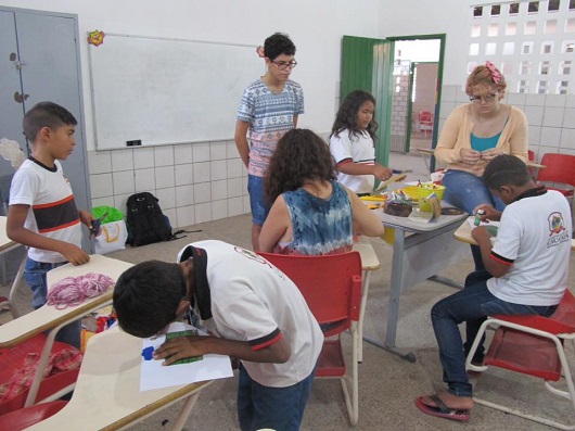 Jovens e crianças em torno de mesas, desenhando e pintando (Foto: Blog Divulgando a Extensão)