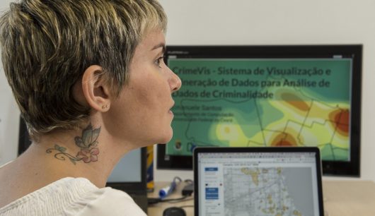 Profª Emanuele Santos em frente a mapa em tela de computador (Foto: Júnior Panela/UFC)