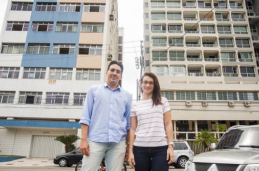 O professor e a professora em frente a dois prédios, que formam um "corredor" atrás deles (Foto: Ribamar Neto/UFC)